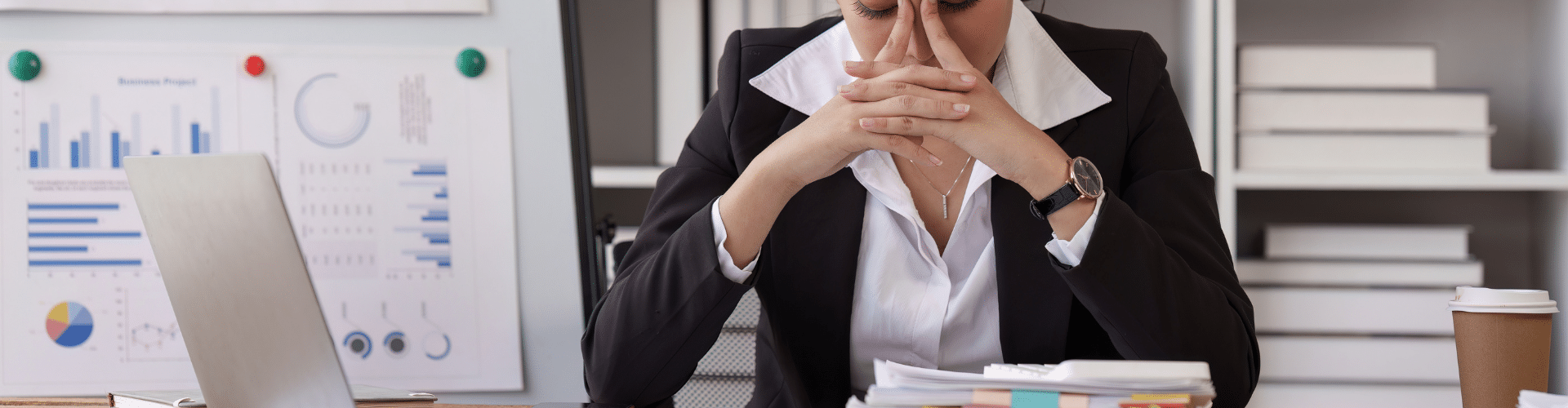 Frustrated businesswoman at desk with financial charts, symbolizing delays and uncertainty in ERC refund process.