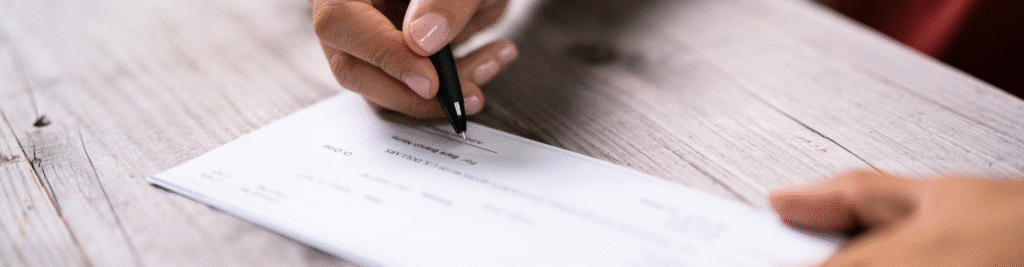 Business owner signing a check, signaling the receipt of their ERC refund check from the IRS.